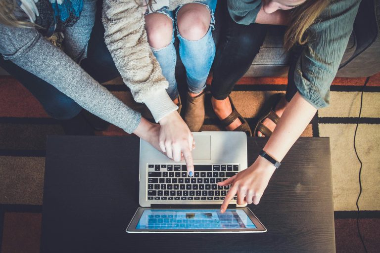 A group of friends searching for cheap flight tickets on a laptop, planning their next trip.