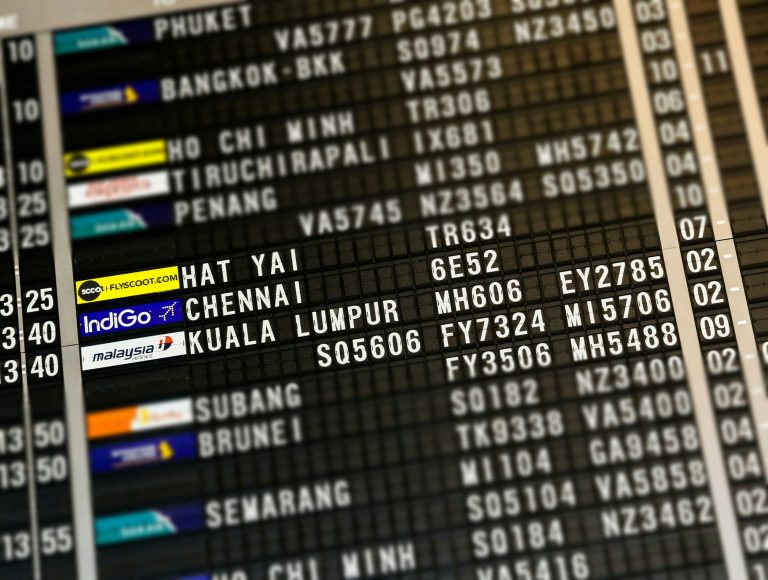 Airport flight board displaying flight details to Chennai and Kuala Lumpur.